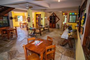 a dining room with tables and chairs and yellow walls at Pousada Aconchego in Pirenópolis