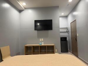 a bedroom with a bed and a flat screen tv on a wall at Casa Motel in Los Angeles +3 photos