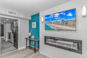 a living room with a tv hanging on a wall at Pristine Oceanfront Oasis With Breathtaking Views- Camelot 1614 in Myrtle Beach