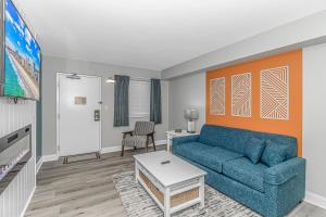 a living room with a blue couch and a table at Pristine Oceanfront Oasis With Breathtaking Views- Camelot 1614 in Myrtle Beach