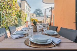 a wooden table with plates and wine glasses on a balcony at Villa Casa Pini by Rent All Como in Bellagio