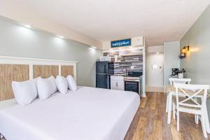 a bedroom with a white bed and a kitchen at Ocean Front Condo Sea Mist 20509 in Myrtle Beach