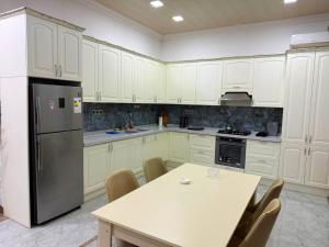 a kitchen with white cabinets and a table and a refrigerator at Şuvelan Villa in Baku