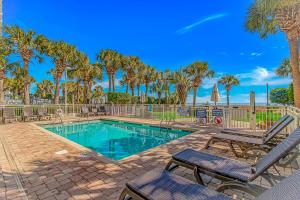 a swimming pool with two chairs and palm trees at Updated 2nd Floor 1BR for 4! Sailfish 210 in Myrtle Beach