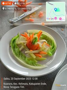 a plate of food with vegetables on a table at Watuburu Cottage & Restaurant in Ende