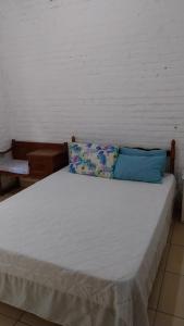 a bed with white sheets and blue pillows on it at Chácara chalé in Juquitiba