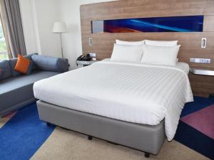 a bedroom with a large bed and a couch at Novotel Taiping in Taiping