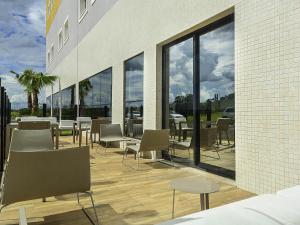 a cafeteria with tables and chairs and windows at ibis Styles Birigui in Birigui