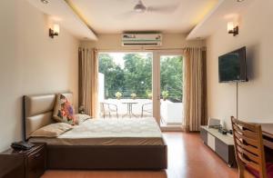 ein Schlafzimmer mit einem Bett und einem Tisch und einem Fernseher in der Unterkunft Amidst Monuments and Serenity in Neu-Delhi