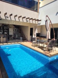 a pool with a table and chairs next to a house at Santorini House Pousada e Restaurante in Araguaína