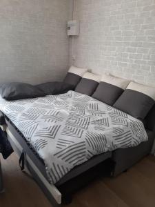 a bed with black and white sheets and a brick wall at Le studio à la campagne in Saint-Gobert +8 photos