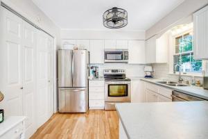 a kitchen with white cabinets and a stainless steel refrigerator at The Seashell Cottage in Ocean City