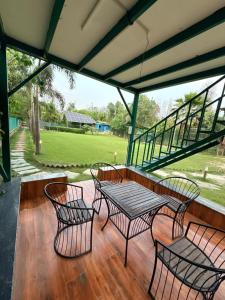 a patio with four chairs and a table on a deck at Luxurious Farm in Greater Noida