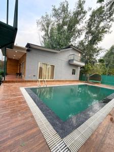 a house with a swimming pool in front of a house at Luxurious Farm in Greater Noida