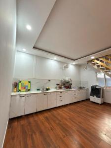 a large kitchen with white cabinets and a wooden floor at Luxurious Farm in Greater Noida