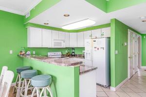 a kitchen with green walls and white cabinets and stools at Lorelei I 404 in Ocean City +10 photos
