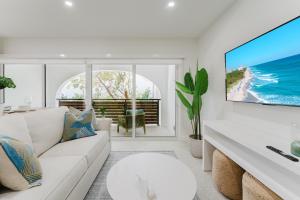 a living room with a white couch and a large screen tv at Casa Luz - Sunlit Boca Pool Retreat in Boca Raton