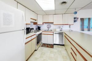 a kitchen with white cabinets and a white refrigerator at Sunny Sands 401 in Ocean City