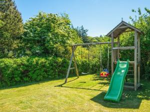 a playground with a green slide in a yard at 4 star holiday home in Ulfborg in Ulfborg