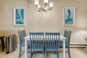 a dining room table with blue chairs and a chandelier at Constellation House 107 in Ocean City +12 photos
