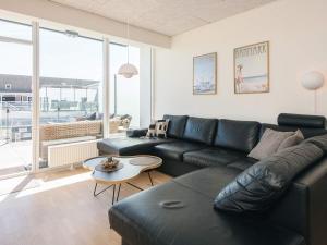 a living room with a black leather couch and a table at 5 star holiday home in Ringkøbing in Ringkøbing +37 photos