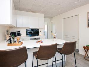 a kitchen with white cabinets and brown chairs at 5 star holiday home in Ringkøbing in Ringkøbing