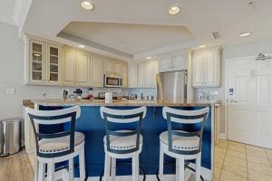 a kitchen with a island with four bar stools at Belmont Towers 410 in Ocean City +25 photos