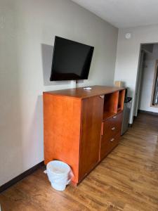 a flat screen tv on top of a wooden dresser at Regency Inn in Muskogee