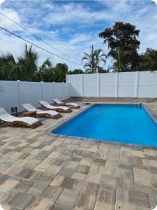 a swimming pool with lounge chairs next to a white fence at Vacation Home with Pool in Bradenton