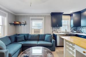 a living room with a blue couch and a kitchen at Straney #3-Sea Renity in Ocean City