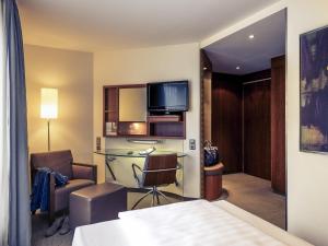 a hotel room with a bed and a desk and a tv at Sunday Hotel München Airport Freising in Freising