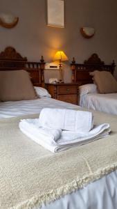 a room with two beds with white towels on them at Hostal Bil in Salduero