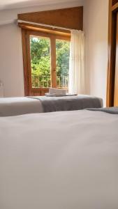 two beds in a room with a window at Hostal Bil in Salduero +1 photo