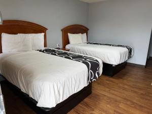 two beds in a hotel room with white sheets at Regency Inn in Muskogee