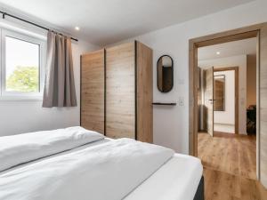a bedroom with a white bed and a wooden wall at Mosers Apartment in Reith im Alpbachtal