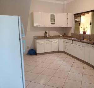 a kitchen with white cabinets and a tile floor at Pousada Exclusiva in Rondonópolis