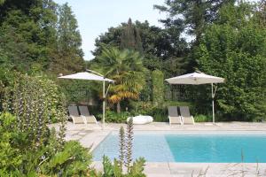 a swimming pool with two umbrellas and chairs and a pool at Gîtes L'Escargot Bleu in Oloron-Sainte-Marie