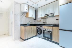 a kitchen with wooden cabinets and a washing machine at Appart-Hôtel Luxury SuiteMar in M'diq