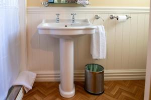a white sink in a bathroom with a trash can at The Station in Hunterville