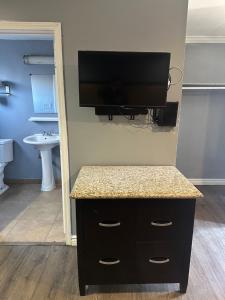 a bathroom with a tv on a wall with a counter at Driftwood Motel in Colton
