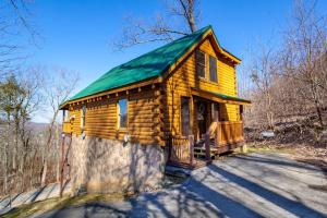 a small wooden cabin with a green roof at Whisk-A-Way - Hot Tub, Pool Table & Jacuzzi! in Abbeyville
