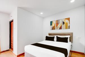 a white bedroom with a white bed and some paintings at Super Townhouse B N Reddy Formerly Capitol Stay Inn in Surūrnagar