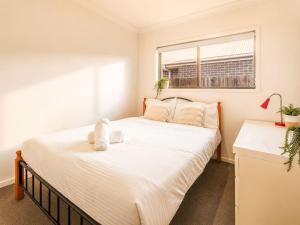 a bedroom with a large white bed with a window at Spacious 4B Near Logan with Parking in Marsden