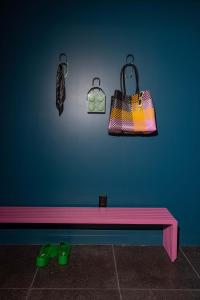 a pink bench against a blue wall with a purse at Hotel Hilo - Room 201 in Louisville