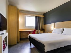 a hotel room with a large bed and a desk at ibis Marilia in Marília