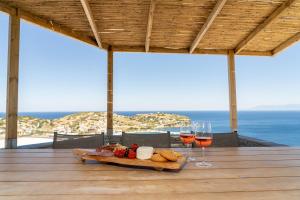 a table with a tray of food and two glasses of wine at PETRA Luxury Villas in Agioi Apostoli