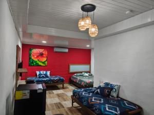 a room with two beds and a red wall at Vicina Maris Beach Lodge in María Chiquita