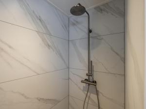 a shower with white marble walls and a shower head at t Sluisje 8 in Bantega