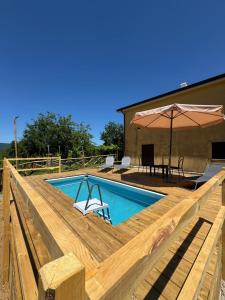 a swimming pool on a wooden deck with an umbrella at GrappoloNero in Laino Castello