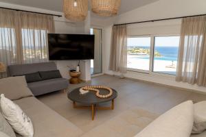 a living room with a couch and a table and a tv at PETRA Luxury Villas in Agioi Apostoli